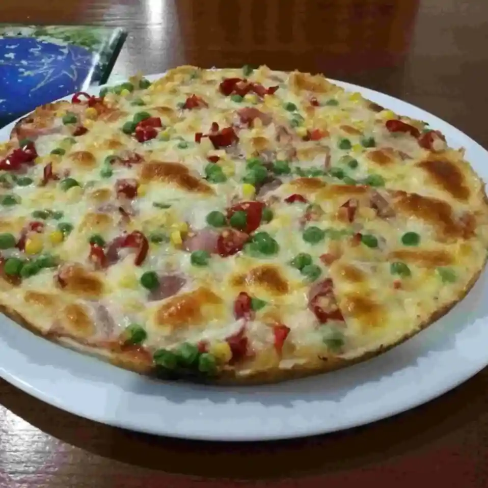 Detailní pohled na pizzu se šunkou a zeleninou.